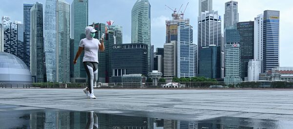 Женщина в защитной маске гуляет по набережной в бухте Марина в Сингапуре. Архивное фото - Sputnik Кыргызстан