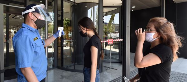 Сотрудник охраны торгового центра у входа проверяет температуру посетителей после ослабления карантинных мер в Бишкеке Сотрудник охраны торгового центра у входа проверяет температуру посетителей после ослабления карантинных мер в Бишкеке - Sputnik Кыргызстан