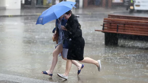 Девушки идут под зонтом во время сильного дождя. Архивное фото  - Sputnik Кыргызстан