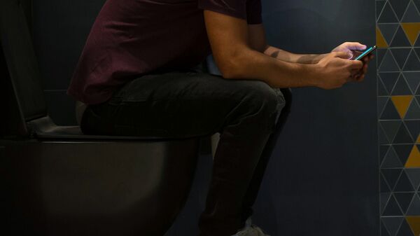 Мужчина пользуется смартфоном сидя на унитазе. Иллюстративное фото - Sputnik Кыргызстан