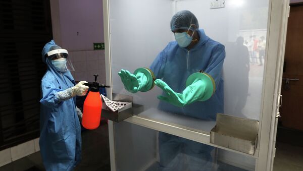 Медицинский работник дезинфицирует перчатки другого мед работника - Sputnik Кыргызстан